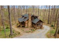 A beautiful log home nestled in the woods with a stone chimney and inviting porches at 2931 Western Hills Ln, Elon, NC 27244