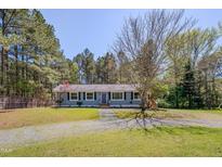 Charming single-story home featuring blue siding, black shutters and a well-manicured front yard with mature trees at 5604 Bobcat Rd, Chapel Hill, NC 27516