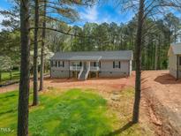 Charming single-story home with a welcoming front porch, surrounded by mature trees and a lush lawn at 7122 Guess Rd, Hillsborough, NC 27278