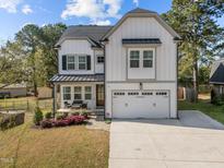 Charming two-story home with white siding, covered porch, and well-manicured landscaping at 802 Knollwood Dr, Apex, NC 27502