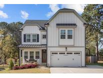 Charming two-story home featuring white board and batten siding and a two-car garage at 802 Knollwood Dr, Apex, NC 27502