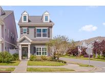 Charming two-story home features dormer windows, gray siding, and a well-manicured front yard with mature landscaping at 900 Ambergate Sta, Apex, NC 27502