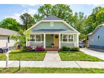 Charming home featuring a welcoming front porch, complemented by lush landscaping and a well-maintained lawn at 1023 Kent St, Durham, NC 27707