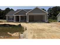 New construction home featuring a two-car garage, gray siding, and covered front porch at 107 Tee Dr, Selma, NC 27576