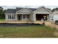 Charming single-story home featuring a two-car garage and covered front porch at 107 Tee Dr, Selma, NC 27576