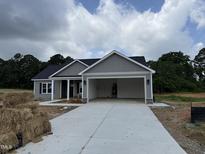 New home with gray siding, black roof, open garage, and concrete driveway at 107 Tee Dr, Selma, NC 27576