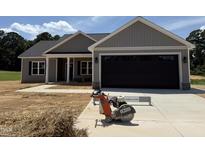 New construction home showing a spacious two-car garage with gray siding and a well-manicured lawn at 107 Tee Dr, Selma, NC 27576