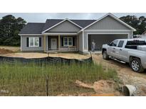 Charming single-story home featuring a gray siding and a welcoming covered porch at 107 Tee Dr, Selma, NC 27576