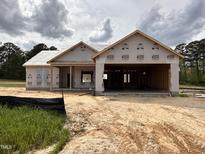 Exterior of home under construction with a garage, wrapped in protective material with dirt lot at 107 Tee Dr, Selma, NC 27576