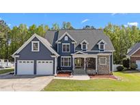 Charming blue two-story home with a well-manicured lawn, stone accents, and a three car garage at 133 Aleah Ct, Clayton, NC 27520