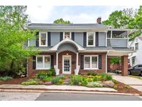 Charming two-story home with a brick facade, grey siding, black shutters and landscaped front yard at 1403 Vickers Ave, Durham, NC 27707