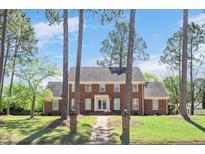 Traditional brick home with mature trees, manicured lawn, and charming brick pathway to the entrance at 1602 Lake Shore Dr, Dunn, NC 28334