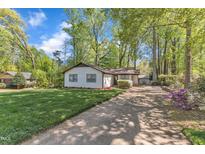 Charming single-story home featuring a well-manicured lawn and a long driveway surrounded by mature trees at 1623 Alicary Ct, Cary, NC 27511