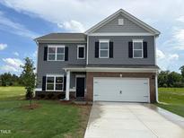 Charming two-story home featuring gray siding, brick accents, and a spacious two-car garage at 164 E Victory View. Ter, Smithfield, NC 27577