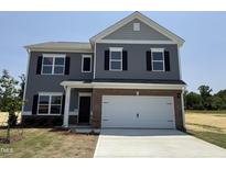 Charming two-story home with gray siding, brick accents, black shutters, and a pristine white garage door at 164 E Victory View. Ter, Smithfield, NC 27577