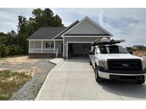 Charming single-story home featuring a covered porch, attached garage, and freshly poured concrete driveway at 192 Royal Ave, Selma, NC 27576