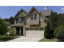Charming two-story home with a light yellow exterior, complemented by a well-maintained front lawn and attached garage at 2012 Longmont Dr, Wake Forest, NC 27587