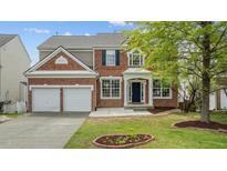 Two-story brick home featuring a two car garage and a well-manicured lawn with lovely landscaping at 211 Kurtner Ct, Morrisville, NC 27560