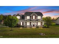 Charming two-story home features a covered front porch and well-manicured lawn, creating an inviting curb appeal at 24 Kaki Ct, Selma, NC 27576