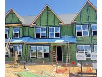 Townhome under construction showcasing windows, green weather barrier, and ladders against a bright blue sky at 3020 White Rail Dr, Fuquay Varina, NC 27526