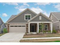 Charming single-Gathering home with a stone and gray shingle facade, two-car garage, and welcoming front porch at 421 Raven Cliff St, Apex, NC 27523