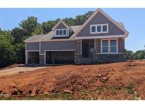 Charming craftsman-style home features a two-car garage, stone accents, and a welcoming covered porch at 4897 Grosbeak Ct, Mebane, NC 27302