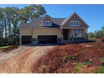 Unfinished two-story home featuring a three-car garage and dormer windows, set against a clear blue sky at 4897 Grosbeak Ct, Mebane, NC 27302