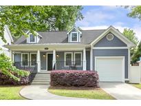 Charming home exterior with blue siding, covered front porch, manicured shrubs, and attached one-car garage at 604 Mills St, Raleigh, NC 27608