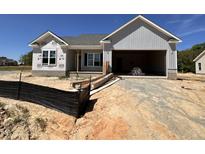 New construction home featuring a two-car garage and unfinished landscaping under a bright blue sky at 69 Tee Dr, Selma, NC 27576