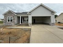 New construction single-Gathering home with a gray exterior, stone accents, and a spacious two-car garage at 69 Tee Dr, Selma, NC 27576