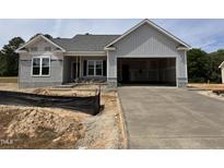 A new construction home featuring an attached two-car garage and freshly poured driveway at 69 Tee Dr, Selma, NC 27576