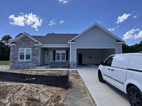 Charming single-story home featuring a stone facade, light gray siding, and an attached two-car garage at 69 Tee Dr, Selma, NC 27576