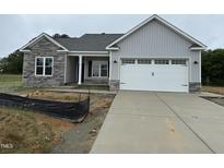 New construction home featuring gray siding, stone accents, and a two-car garage at 69 Tee Dr, Selma, NC 27576