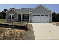 Charming new construction home with stone accents, gray siding, and attached two-car garage at 69 Tee Dr, Selma, NC 27576