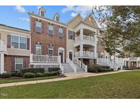 Charming townhome showcasing a well-manicured lawn, inviting entryway, and brick facade with elegant purple shutters at 10410 Sablewood Dr # 111, Raleigh, NC 27617