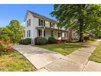 Charming two-story home with white siding, black shutters, a cozy front porch, and landscaped front yard at 116 W Front St, Oxford, NC 27565