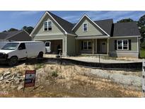 New home construction featuring green siding, a dark roof, and an attached garage at 125 Tee Dr, Selma, NC 27576