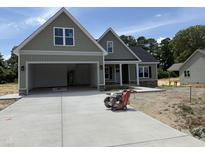Newly constructed home featuring a large two-car garage, stone accents and an extended concrete driveway at 125 Tee Dr, Selma, NC 27576