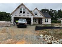 New construction home showing the front exterior with an attached garage in a partially developed lot at 125 Tee Dr, Selma, NC 27576