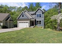 Charming two-story home with a well-manicured lawn and attached garage, nestled amongst mature trees at 1401 Freshwater Ct, Wake Forest, NC 27587