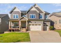 Beautiful two-story home with a manicured lawn, covered porch, and a three car attached garage at 212 Blue Granite Dr, Holly Springs, NC 27540