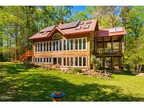 Charming wooden home with large windows and a red metal roof nestled among lush greenery at 2281 Lamont Norwood, Pittsboro, NC 27312