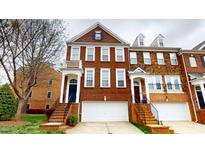Brick townhome with attached garages, a covered entryway, and a stairway to the front door at 2750 Laurelcherry St, Raleigh, NC 27612