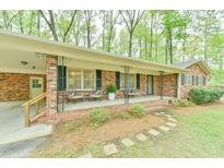Inviting brick home features a covered front porch with seating and mature trees at 775 Old Graham Rd, Pittsboro, NC 27312