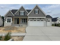 Charming two-story home with gray shake siding, a three-car garage, and unfinished front yard at 921 Lily Claire Ln, Fuquay Varina, NC 27526