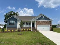 Charming single-story home featuring a manicured lawn, stone accents, and a two-car garage at 11470 International Dr, Middlesex, NC 27557
