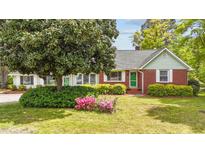 Charming single story brick home with lush landscaping, mature tree, and green front door at 1410 Cross Link Rd, Raleigh, NC 27610