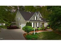Charming two-story home with a well-manicured lawn, lush greenery, and a private driveway leading to an attached garage at 144 W Walker Woods Ln, Clayton, NC 27527