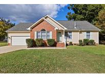 Charming home featuring a manicured lawn, brick accents, and inviting curb appeal at 1601 Entheos Ln, Raleigh, NC 27610