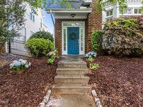 Charming brick home featuring a blue front door adorned with a wreath and surrounded by lush landscaping at 1640 Legendary Ln, Morrisville, NC 27560